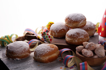 German donuts with jam and icing sugar. Carnival powdered sugar raised donuts with paper streamers.