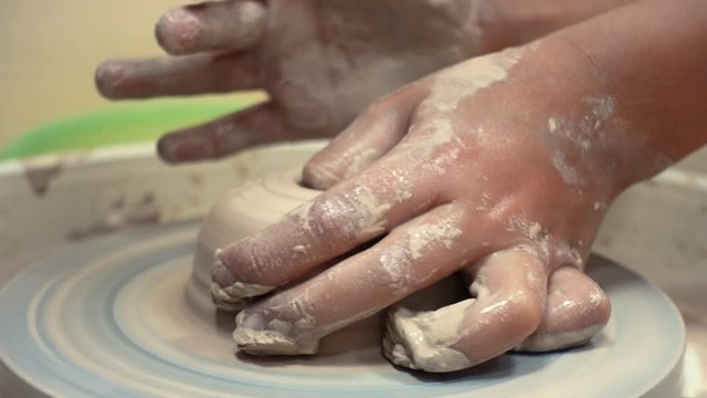 child hands making a clay pottery
