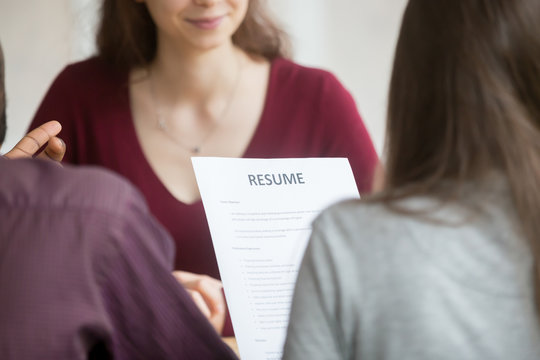 Multiracial hr holding resume at job interview with woman candidate, recruitment team read applicant cv at hiring negotiations concept, human resources recruiters with curriculum vitae, close up view