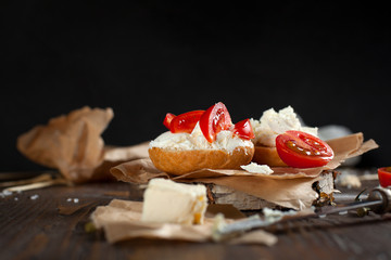 Toast with feta cheese on baking paper, cherry tomatoes and butter on a dark wooden table