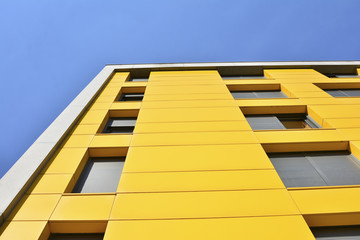 Yellow building with windows and blue sky - Powered by Adobe