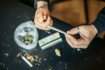 Close up of addict lighting up marijuana joint with lighter