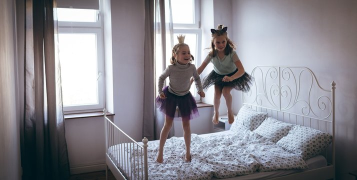 Sisters in costume playing on bed
