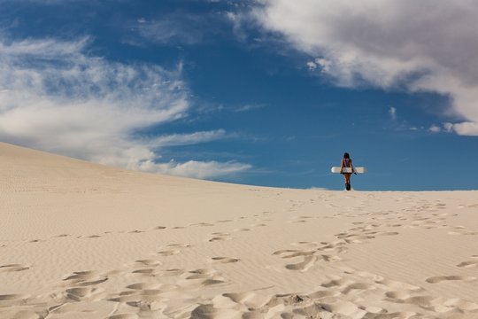 Woman with sandboard standing in the desert