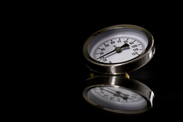 A clock thermometer for measuring the temperature with a reflection in the mirror. Thermometer on a glass mirror table.