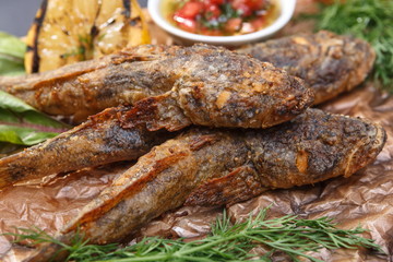 Fried fish goby with sauce on a wooden board