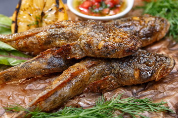 Fried fish goby with sauce on a wooden board