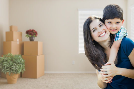 Young Mother and Son Inside Empty Room with Moving Boxes.