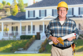 Contractor With Plans and Hard Hat In Front of Beautiful Custom House.