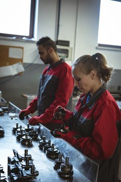 Two workers checking machine parts