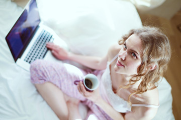 Young beautiful woman sitting in bed with laptop.