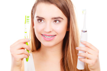 Woman with braces holding electric and traditional toothbrush