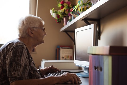 Side view of senior woman working on computer at home