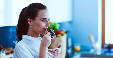 Happy woman drinking tea in the kitchen at home