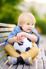 Little boy resting after playing a soccer/football game on summer day