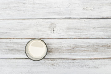 Fresh milk in glass on white wood floor top view