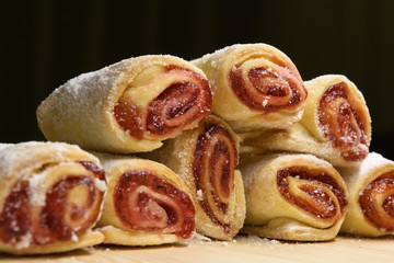 Delicious sweet rolls with red jam stacked on wood desk