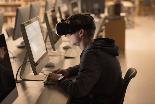 Teenage boy using virtual reality headset while studying