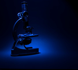 Microscope isolated against blue and black background with blank copy space