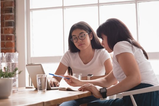 Female executives discussing over laptop