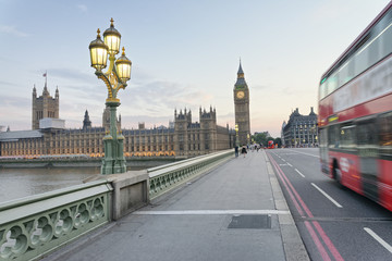 Fototapeta na wymiar Red bus speeding up along Westminster Bridge at sunset, London - UK
