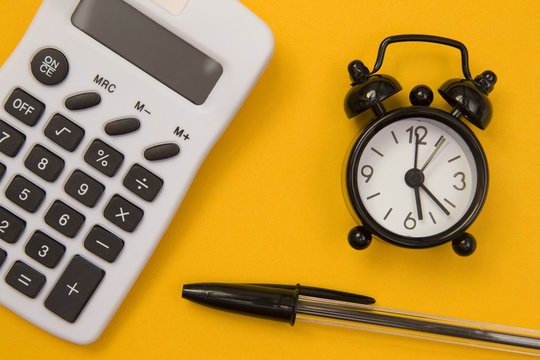 An Old Fashioned Alarm Clock, Calculator and a Pen - The deadline for calculating 