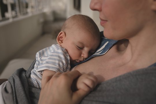 Young mom holding sleeping baby at home