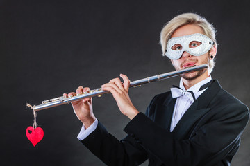 man in carnival mask playing flute