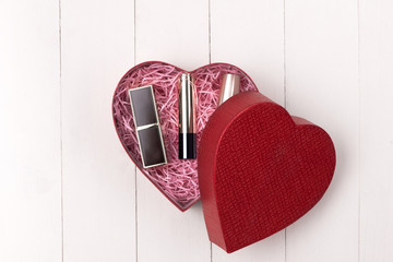 Makeup cosmetics in heart shape box on wooden table. Fflat lay. Top view