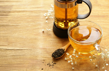 kettle French press with fragrant tea on a wooden table