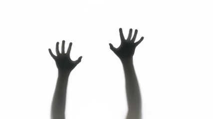 Silhouette of a zombie trying to get through a glass window. Great for Halloween.