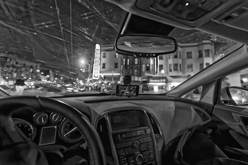 Driving along city traffic at night, view from car interior