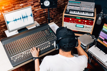 asian male music producer, sound engineer, composer, dj working in studio. recording, broadcasting, audio video editing concept