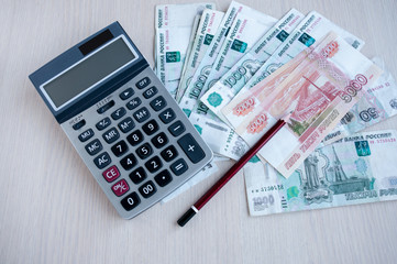 On the table are money Russian rubles, a calculator and a pencil. Profit calculation