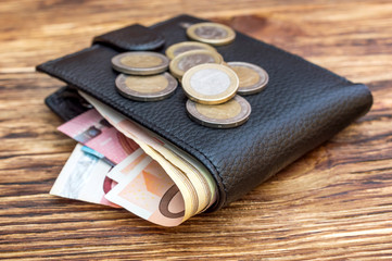 Wallet with euro bills and euro coins on wooden table. Business concept.