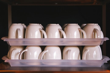 Pure ceramic mugs on a tray. Stack of Coffee cups in restaurant.