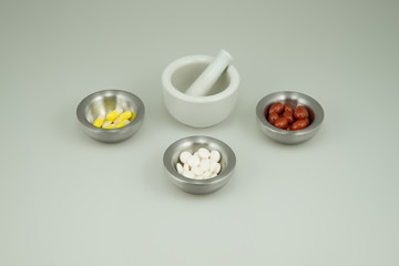 Colorful medications on a light background with a mortar and pestle