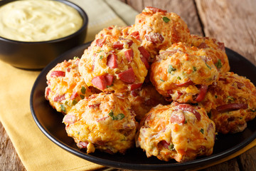 simple tasty snack of sausage balls with cheese cheddar and greens on a plate and sauce close-up. horizontal