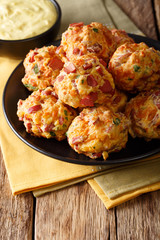 Freshly baked sausage balls with cheese cheddar on a plate and mustard sauce close-up. vertical