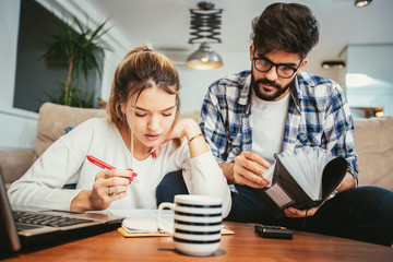 Woman and man doing paperwork together, paying taxes online on notebook pc