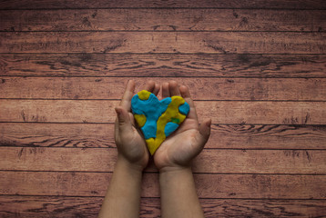World Down syndrome day with blue yellow awareness heart holding by a child on wooden background...