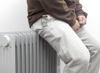 the freezing man sitting and heating his ass on oil heater