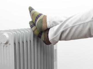 Two feet placed on a heater for warmth. Winter holidays concept.