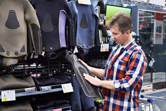 Man Chooses Wetsuit And Fins For Spearfishing In Sports Shop