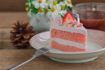 White chocolate strawberry yogurt cake decorated with fresh fruits and chocolate chunk on wood table with copy space. Delicious and sweet pink cake for Valentines or birthday. Homemade bakery concept.