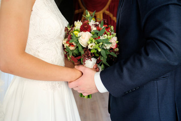 Obraz na płótnie Canvas bride and groom play handies and keep bouquet on hands