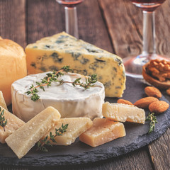Cheese, nuts, honey and red wine on wooden background.