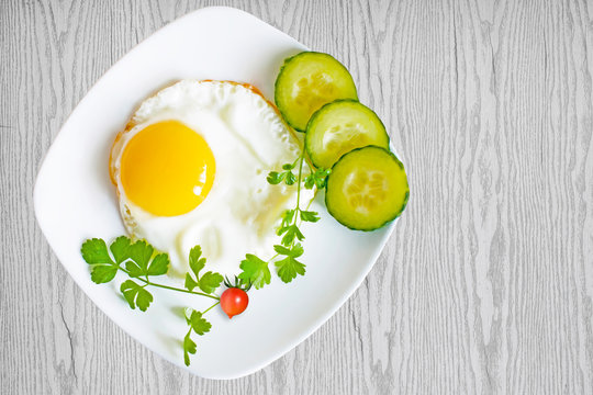Scrambled eggs with cucumbers and tomatoes on plate on wooden table, top view
