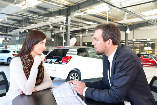 Verkaufsgespräch im Autohandel - Verkäufer berät junge Frau über Kauf eines KFZ´s // Sales talk in the car trade - salesman advises young woman on the purchase of a car
