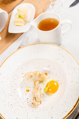 Broth with dumplings and an egg yolk being served in a jug in a restaurant